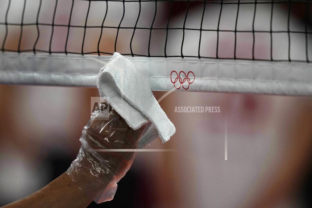 Frank Augstein A steward uses a plastic glove and a cloth to disinfect the volleyball net during a rehearsal before the start of the volleyball preliminaries at Ariake Arena at the 2020 Summer Olympics, Friday, July 23, 2021, in Tokyo, Japan. (AP Photo/Frank Augstein)