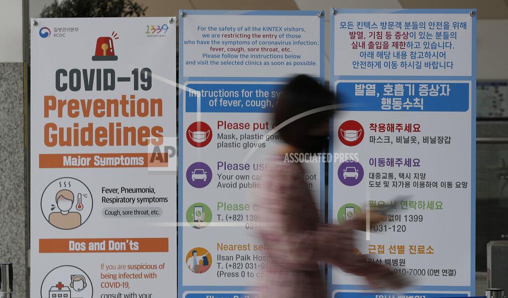 Lee Jin-Man A woman wearing a face mask walks near a banner showing precautions against the new coronavirus at an exhibition and convention center in Goyang, South Korea, Friday, June 12, 2020. (AP Photo/Lee Jin-man)
