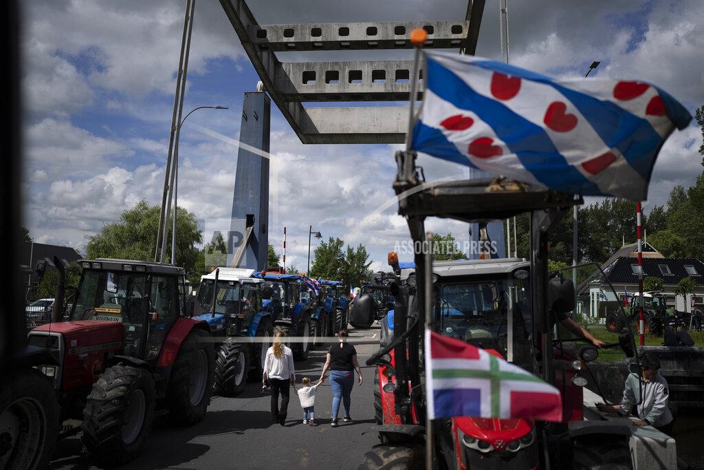 Peter Dejong The flag of the Frysian province flies from a tractor as protesting farmers block a draw bridge at locks in the Princess Margriet canal, preventing all ship traffic from passing in Gaarkeuken, northern Netherlands, Monday, July 4, 2022. Dutch farmers angry at government plans to slash emissions also used tractors and trucks Monday to blockade supermarket distribution centers, the latest actions in a summer of discontent in the country's lucrative agricultural sector. (AP Photo/Peter Dejong)
