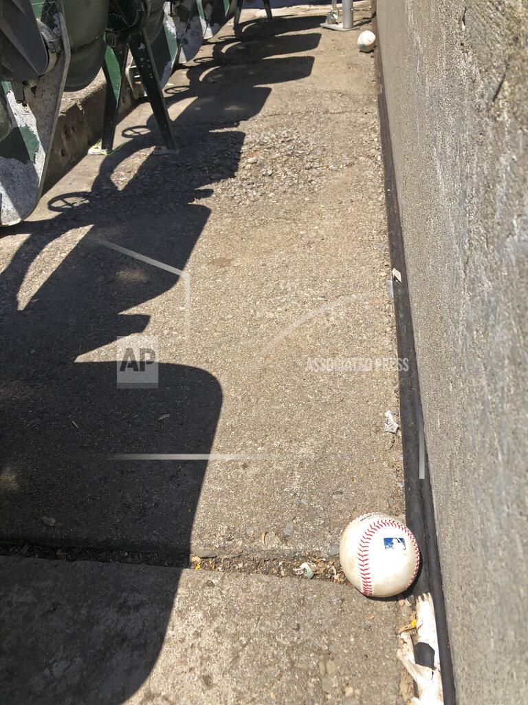 Ben Margot Baseballs fouled off by players are seen stopped at the bottom row of the Oakland Coliseum after rolling down through empty stands during the baseball game between the Los Angeles Angels and the Oakland Athletics on Monday, July 27, 2020, in Oakland, Calif. (AP Photo/Ben Margot)