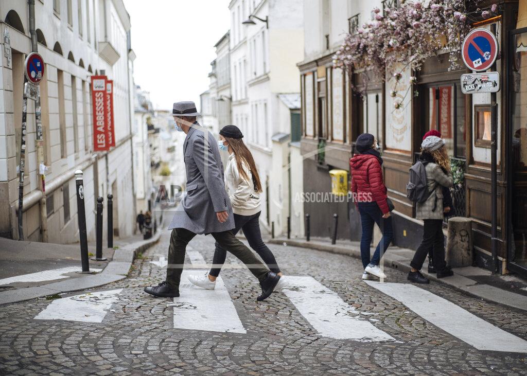 Lewis Joly People wearing face masks walk, in the Montmartre district of Paris, Sunday Oct. 25, 2020. A curfew intended to curb the spiraling spread of the coronavirus, has been imposed in many regions of France including Paris and its suburbs. (AP Photo/Lewis Joly)
