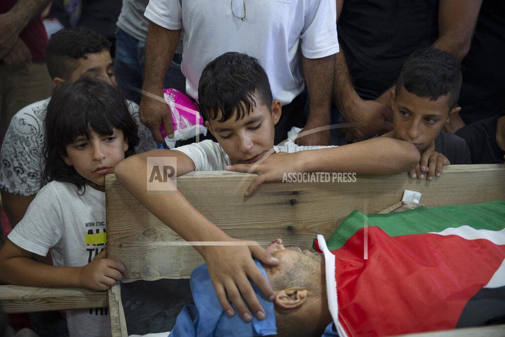 Majdi Mohammed Palestinian Yousef Jadallah, places his hand on his father Raed Jadallah's body, who was killed by Israeli forces at the western entrance of his village while returning from work in the early hours of Wednesday morning, during his funeral, in the West Bank village of Beit Ur al-Tahta, Wednesday, Sep. 1, 2021. (AP Photo/Majdi Mohammed)