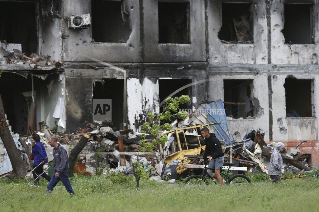 Alexei Alexandrov People walk past a destroyed building in Mariupol, in territory under the government of the Donetsk People's Republic, eastern Ukraine, Saturday, May 21, 2022. (AP Photo/Alexei Alexandrov)