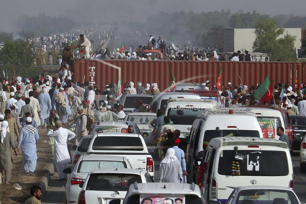 Mohammad Zubair Supporters of ousted Prime Minister Imran Khan remove shipping containers placed by authorities to stop them at a highway during their march toward Islamabad, in Swabi, Pakistan, Wednesday, May 25, 2022. Pakistani police have fired tear gas and scuffled with stone-throwing supporters of Khan as they gathered for planned marches Wednesday toward central Islamabad. The defiant former premier had called followers to a rally outside Parliament to bring down the government and force early elections. (AP Photo/Mohammad Zubair)