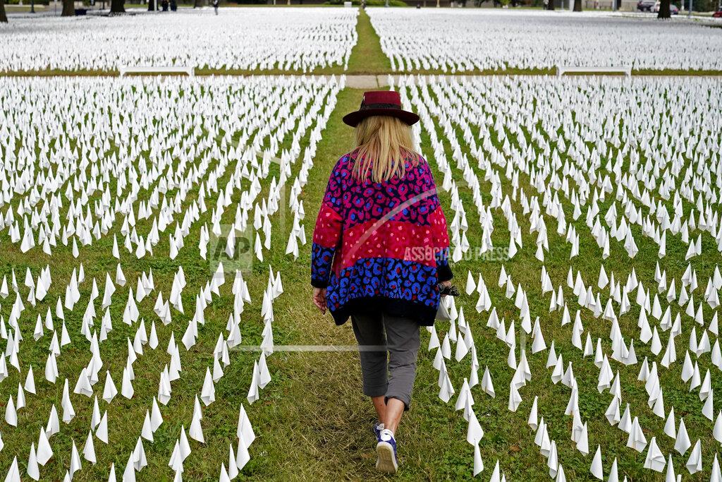 Patrick Semansky FILE - In this Oct. 27, 2020, file photo, Artist Suzanne Brennan Firstenberg walks among thousands of white flags planted in remembrance of Americans who have died of COVID-19 near Robert F. Kennedy Memorial Stadium in Washington. Firstenberg's temporary art installation, called "In America, How Could This Happen," will include an estimated 240,000 flags when completed. (AP Photo/Patrick Semansky, File)