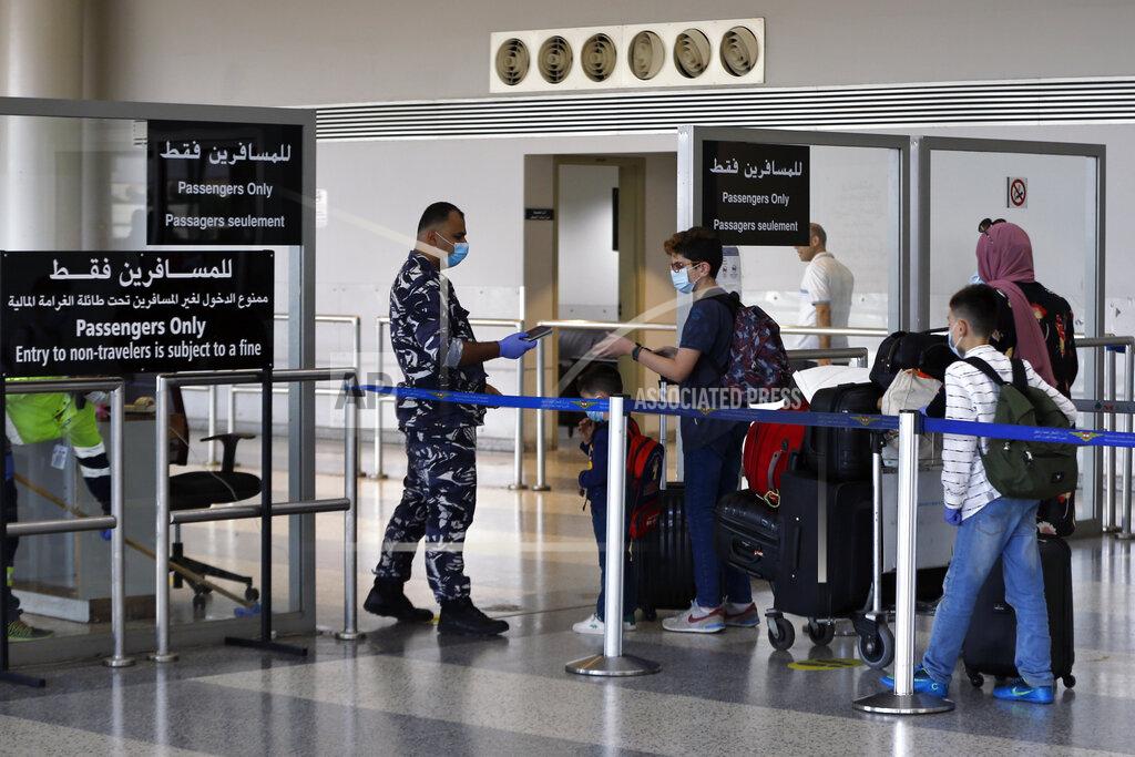 Bilal Hussein A Lebanese officer checks passports of travelers at the departure terminal of the Rafik Hariri International Airport in Beirut, Lebanon, Wednesday, July 1, 2020. Beirut's airport is partially reopening after a three-month shutdown and Lebanon's cash-strapped government is hoping that Thousands of Lebanese expatriates will return for the summer, injecting dollars into the country's sinking economy. (AP Photo/Bilal Hussein)