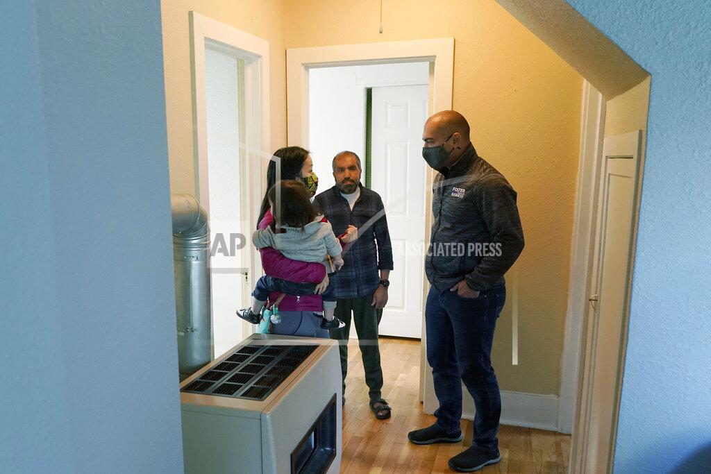Ted S. Warren Thuy Do, left, and her husband, Jesse Robbins, right, talk with Abdul, center, Monday, Sept. 20, 2021, about a minor plumbing issue in the vacant rental home owned by the couple that they have provided Abdul — who worked as a mechanic before leaving Kabul, Afghanistan about a month ago — as a place to live with his family until they can find more permanent housing. Do was nine years old when her family arrived in the United States from Vietnam in the 1980s, and that memory led Do and Robbins to reach out to assist Afghans fleeing their country. (AP Photo/Ted S. Warren)