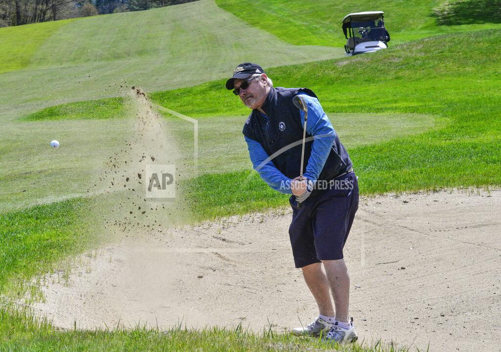 Chris Huffman, of Brattleboro, Vt., chips his ball out of a sand trap while playing golf at the Brattleboro Country Club, Friday, May 8, 2020, in Brattleboro, Vt.. Golfers return to the course after a delayed opening because of the COVID-19 pandemic. (Kristopher Radder/The Brattleboro Reformer via AP)