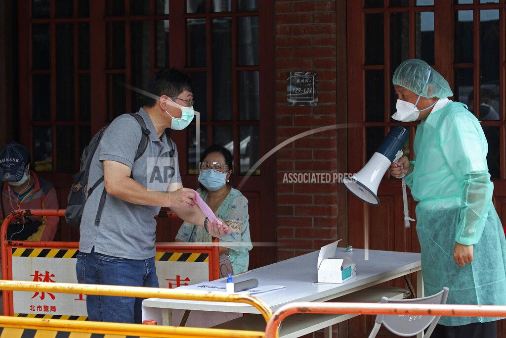 Chiang Ying-Ying FILE - In this May 18, 2021, file photo, a medical staff wearing protective gear, guides people at a rapid coronavirus testing center after the infection alert rose to level 3 in Taipei, Taiwan. After a year of success, Taiwan is struggling with its largest outbreak since the pandemic began. When locally transmitted cases started being found in May 2021, it soon became clear that the central government was ill prepared not only to contain them, but to even detect them on a large scale due to a lack of investment in and a bias against rapid testing. (AP Photo/Chiang Ying-ying, File)