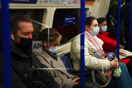 Commuters in a London underground tube train wear face masks to curb the spread of COVID-19, now mandatory on public transport in Britain after the emergence of new Omicron variant, in London, Tuesday, Nov. 30, 2021. (Victoria Jones/PA via AP)