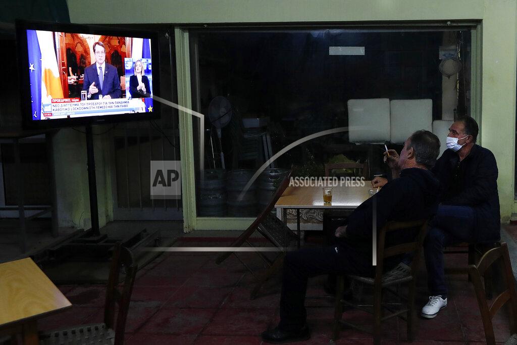Petros Karadjias Two men sit at a social club and watch the televised address of Cypriot President Nicos Anastasiades explaining the need for additional restrictions to beat back a surge in COVID-19 cases in Nicosia suburb of Lakatamia, Cyprus, on Tuesday, Nov. 11, 2020. Cyprus has put its entire southwest under a strict 19-day lockdown, banning any non-essential movement of people and shuttering bars and restaurants after a string of escalating restrictions failed to curb a sharp increase in COVID-19 infections. (AP Photo/Petros Karadjias)