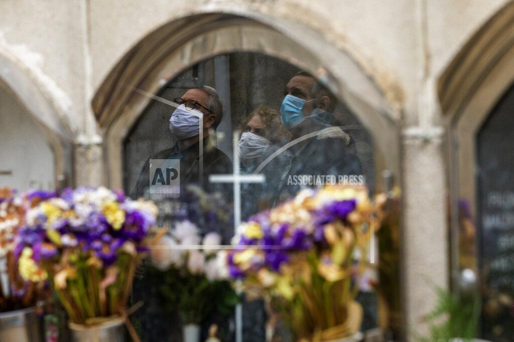 Emilio Morenatti A woman next to her husband, left, and her brother, right, attend the funeral of their mother who died of coronavirus at the Poble Nou cemetery in Barcelona, Spain, Saturday, April 18, 2020. (AP Photo/Emilio Morenatti)