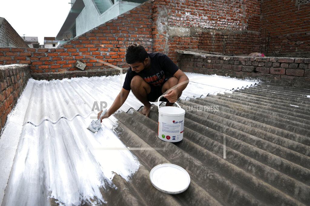 Ajit Solanki A person paints his rooftop with cool white reflective paint which brings down indoor temperature in summer, in Ahmedabad, India, Monday, May 23, 2022. The intense heat wave sweeping through South Asia was made more likely due to climate change and it is a sign of things to come. An analysis by international scientists said that this heat wave was made 30-times more likely because of climate change, and future warming would make heat waves more common and hotter in the future. (AP Photo/Ajit Solanki)
