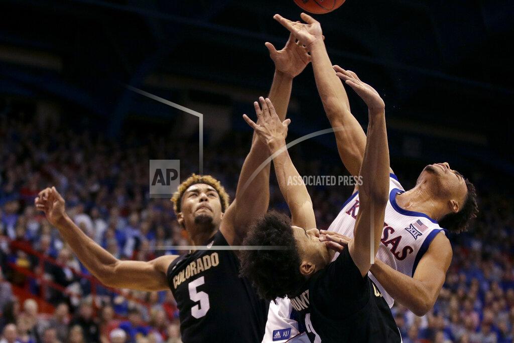 Charlie Riedel Kansas' Devon Dotson, back, shoots under pressure from Colorado's D'Shawn Schwartz (5) and Daylen Kountz during the first half of an NCAA college basketball game Saturday, Dec. 7, 2019, in Lawrence, Kan. (AP Photo/Charlie Riedel)