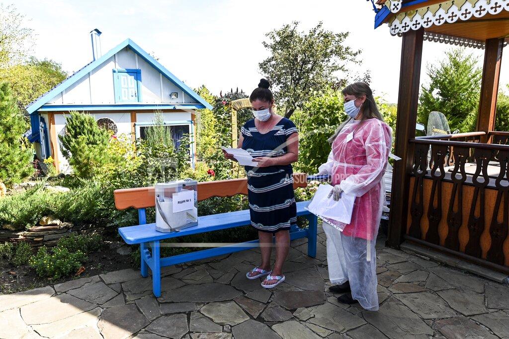 Uncredited A woman reads her ballot as a member of an election commission stands near at a house in Starozolotovsky village, 160 km (100 miles) north of Rostov-on-Don during the Parliamentary elections , Russia, Saturday, Sept. 18, 2021. Sunday is the last of three days voting for a new parliament, but there seems to be no expectation that United Russia, the party devoted to President Vladimir Putin, will lose its dominance in the State Duma. (AP Photo)