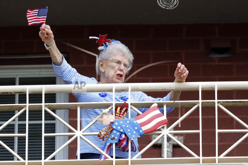 Gerald Herbert FILE - In this March 20, 2020 file photo, a resident of the Lambeth House, where a cluster of the coronavirus has formed, reacts from her balcony as opera singers Irini Hymel and Bryan Hymel sing to the quarantined residents in New Orleans. Where political divides marred early recovery efforts after Hurricane Katrina in 2005, Louisiana is showing rare political unity in the fight against the new coronavirus. (AP Photo/Gerald Herbert, File)