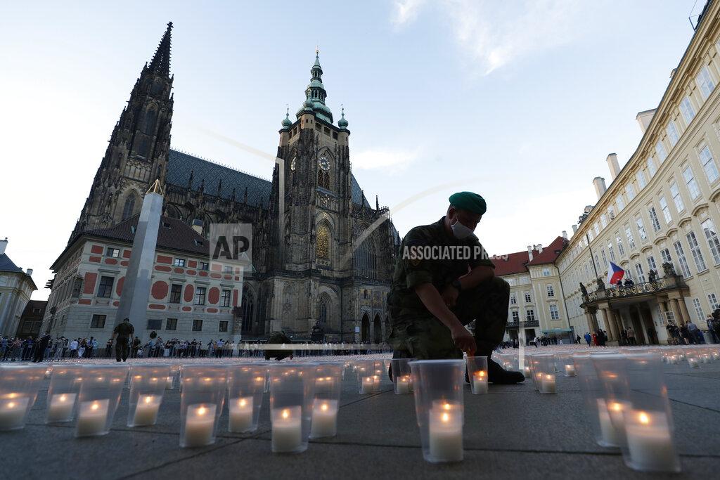 Petr David Josek A soldier lights up a candle to commemorate victims of the COVD-19 pandemic at the Prague Castle in Prague, Czech Republic, Monday, May 10, 2021. The Czech Republic is massively relaxing its coronavirus restrictions as the hard-hit nation pays respect to nearly 30,000 dead. (AP Photo/Petr David Josek)