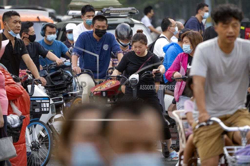 Mark Schiefelbein People wearing face masks to protect against COVID-19 ride bicycles across an intersection during the morning rush hour in Beijing, Wednesday, Aug. 4, 2021. The coronavirus’s delta variant is challenging China’s costly strategy of isolating cities, prompting warnings that Chinese leaders who were confident they could keep the virus out of the country need a less disruptive approach. (AP Photo/Mark Schiefelbein)
