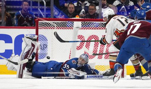 Anaheim Ducks left wing Sonny Milano, back, right, flips the puck in for a goal past Colorado Avalanche goaltender Darcy Kuemper, left, as left wing Tyson Jost comes in to defend in the first period of an NHL hockey game Wednesday, Nov. 24, 2021, in Denver. (AP Photo/David Zalubowski)