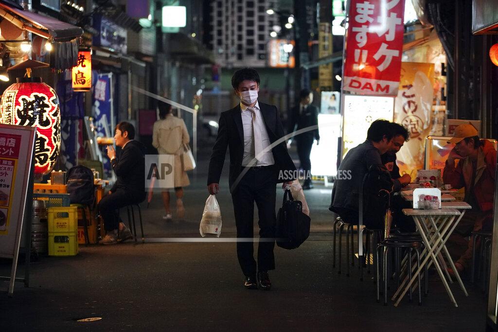Eugene Hoshiko FILE - In this April 28, 2020, file photo, a man wearing a face mask against the spread of the new coronavirus walks through a bar street in Tokyo. Under Japan's coronavirus state of emergency, people have been asked to stay home. Many are not. Some still have to commute to their jobs despite risks of infection, while others are dining out, picnicking in parks and crowding into grocery stores with scant regard for social distancing. (AP Photo/Eugene Hoshiko, File)