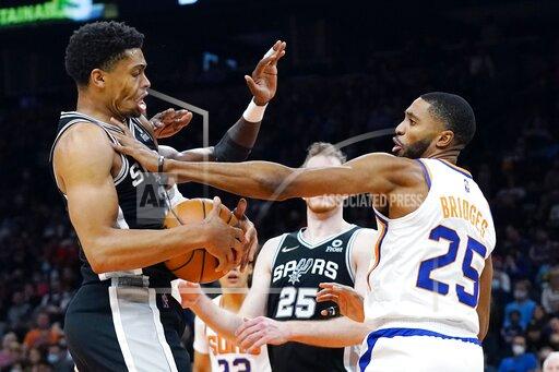 Phoenix Suns forward Mikal Bridges (25) fouls San Antonio Spurs forward Keldon Johnson (3) during the first half of an NBA basketball game Monday, Dec. 6, 2021, in Phoenix. (AP Photo/Ross D. Franklin)