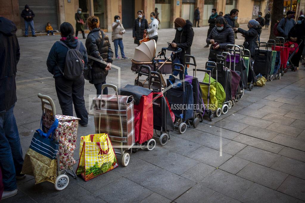 Emilio Morenatti Shopping trollies lined up next to their owners, waiting their turn to receive a weekly pack of donated food and supplies, outside a church in Barcelona, Spain, Wednesday, Feb. 3, 2021. Food requests have increased considerably in the last months as Spain has been in lockdown due to the coronavirus pandemic. (AP Photo/Emilio Morenatti)