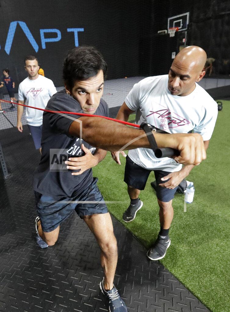 Wilfredo Lee In this Thursday, June 4, 2020 photo, ADAPT gym owners Jorge Sanchez, right, and Scott Grondin, rear, look on as Joaquin Valente demonstrates a workout at the gym in North Miami, Fla. Grondin and Sanchez just got the OK to reopen their Miami area studio Monday after three months. Desperate to keep their carefully built 15-person team, they gave up their own salaries to keep the entire staff at full pay, relying on them to quickly pivot to online fitness training. (AP Photo/Wilfredo Lee)