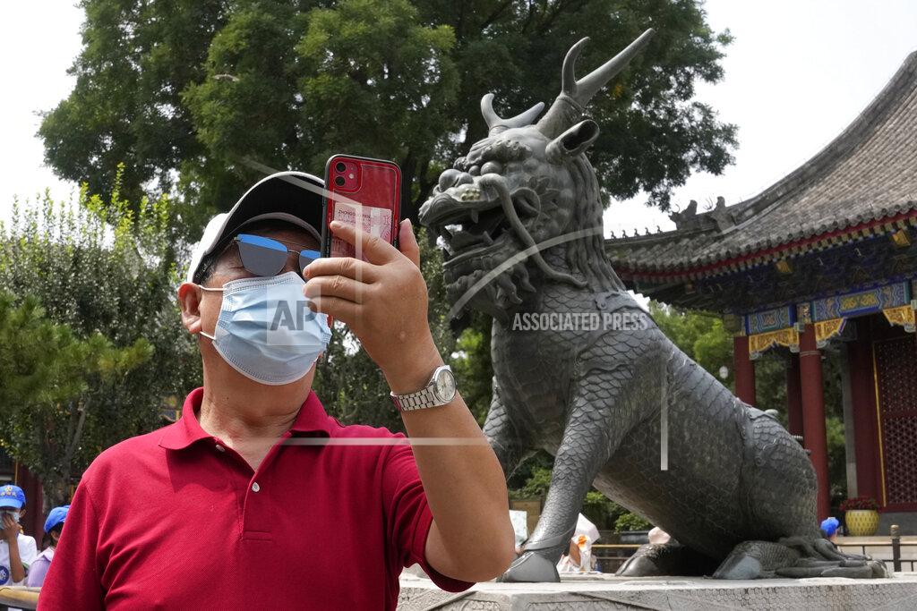 Ng Han Guan A tourist takes a photo near a statue of a mystical beast at the Summer Palace in Beijing Tuesday, Aug. 3, 2021. The current coronavirus outbreaks in China, while still in the hundreds of cases in total, have spread much more widely than previous ones, reaching multiple provinces and cities including the capital, Beijing. Many of the cases have been identified as the highly contagious delta variant that is driving a resurgence in many countries. (AP Photo/Ng Han Guan)