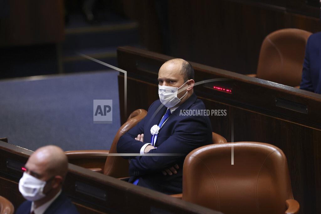 Alex Kolomoisky Israeli Knesset member Naftali Bennett from the Yamina party, center, attends the swearing-in ceremony for Israel's 24th government, at the Knesset, or parliament, in Jerusalem, Tuesday, April 6, 2021. The ceremony took place shortly after the country's president asked Netanyahu to form a new majority coalition, a difficult task given the deep divisions in the fragmented parliament. (Alex Kolomoisky/Pool via AP)