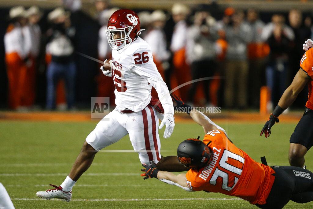 Sue Ogrocki Oklahoma running back Kennedy Brooks (26) avoids a tackle by Oklahoma State safety Malcolm Rodriguez (20) in the fist half of an NCAA college football game in Stillwater, Okla., Saturday, Nov. 30, 2019. (AP Photo/Sue Ogrocki)