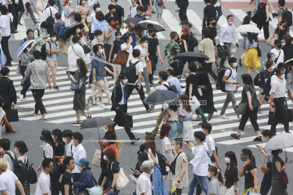 Koji Sasahara People wearing face masks to protect against the spread of the coronavirus cross a street in Tokyo, Wednesday, July 28, 2021. Tokyo Gov. Yuriko Koike on Wednesday urged younger people to cooperate with measures to bring down the high number of infections and get vaccinated, saying their activities are key to slowing the surge during the Olympics. (AP Photo/Koji Sasahara)