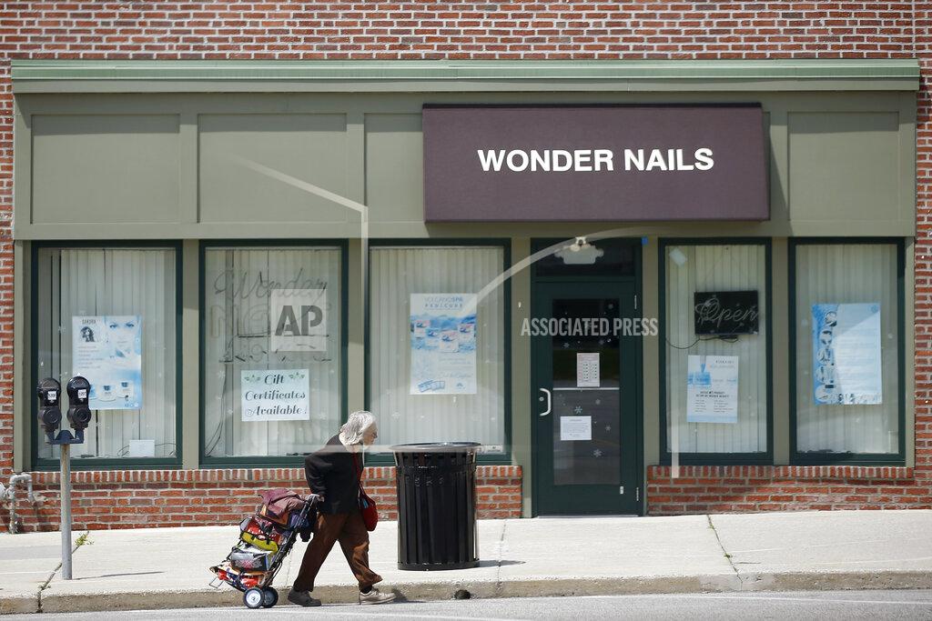 A person walks past a row of closed businesses, Wednesday, April 29, 2020, in Upper Darby, Pa. Devastated by the coronavirus, the U.S. economy is sinking. Now, as some businesses in a few states start to trickle back to work, hopes are beginning to arise that the economy, damaged as it is, might be poised to rebound by the second half of the year. (AP Photo/Matt Slocum)