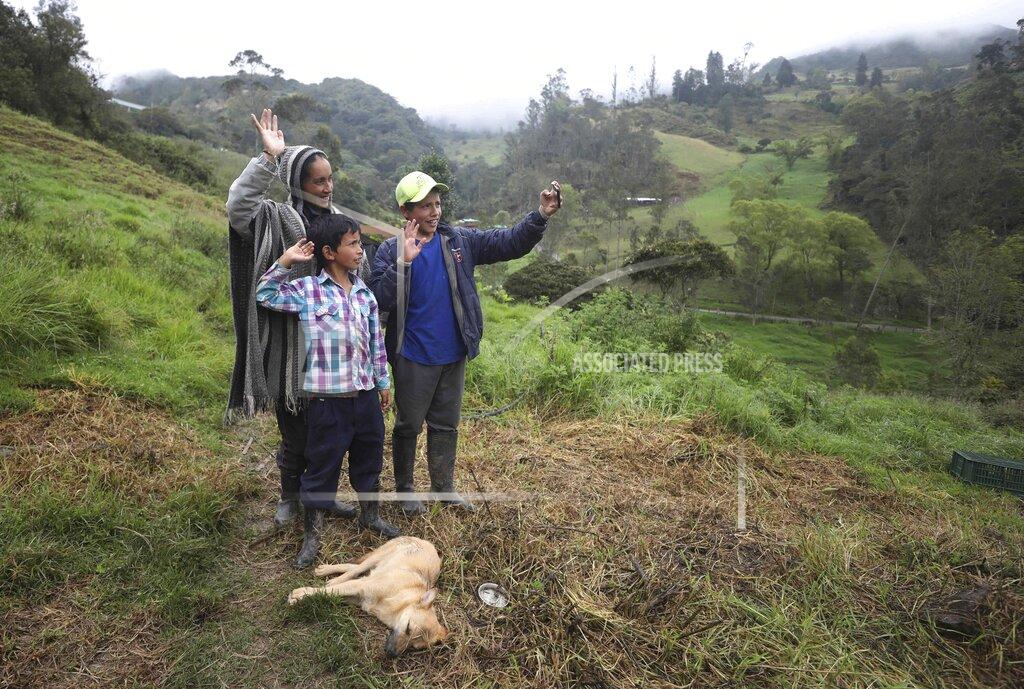 Fernando Vergara Nubia Rocio Gaona, 37, and her sons, David, 14, right, and Jeimmer, 9, record themselves for their online followers, in Chipaque, Colombia, Saturday, May 9, 2020. The small-time farming mother and two sons are reinventing themselves as YouTubers due to a quarantine ordered by the government to contain the spread of COVID-19, teaching others how to grow vegetables at home and providing self-starter kits that they deliver through a local courier. (AP Photo/Fernando Vergara)