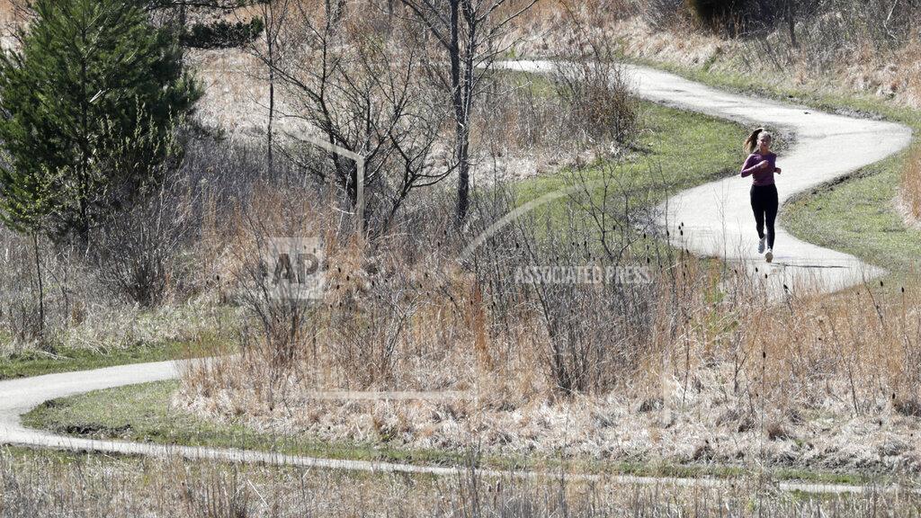 A woman jogs at Beachwood City Park West, Monday, April 20, 2020, in Beachwood, Ohio. (AP Photo/Tony Dejak)