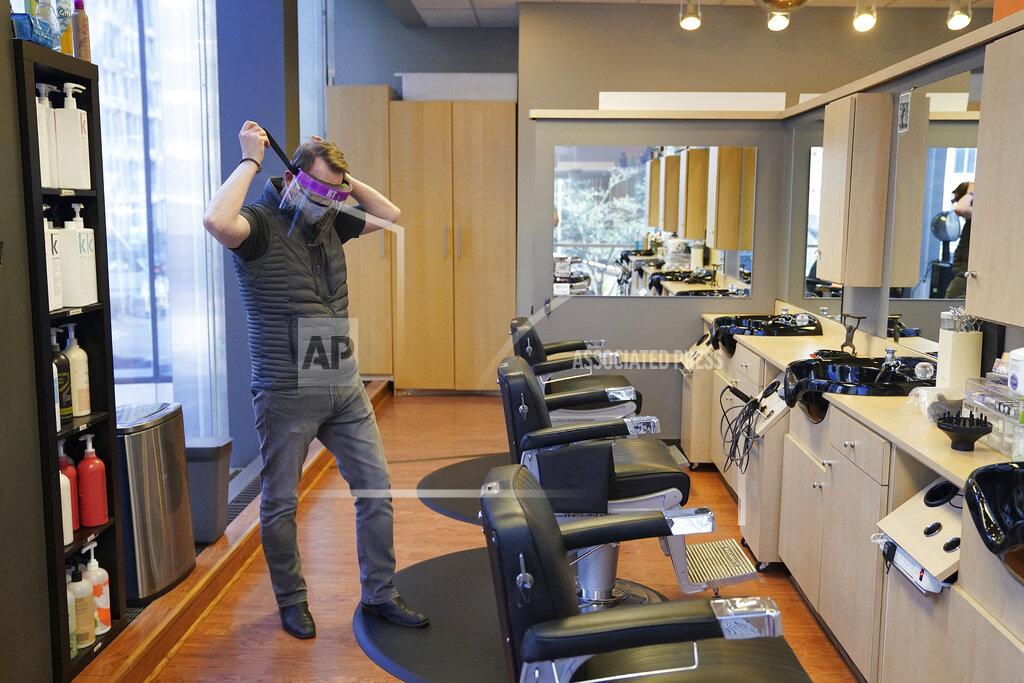 Anthony Souffle Tom Ford, owner of the Madison & Co Salon in the Canadian Pacific building, puts on one of the protective face shields he ordered to wear while cutting hair as he stopped in to get the mail and check in on the space amid the coronavirus pandemic, Wednesday, May 20, 2020, in Minneapolis. Ford had been planning on operating at 50 percent capacity once they reopened before learning the new regulations require a 25 percent capacity. (Anthony Souffle/Star Tribune via AP)