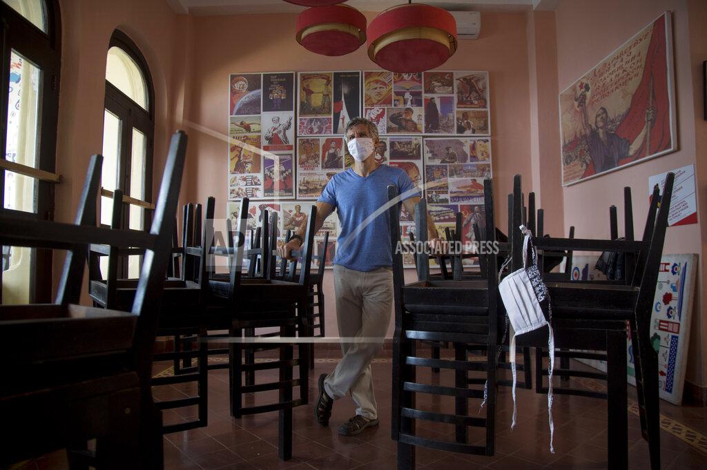 Ismael Francisco Gregory Biniowsy, a Canadian citizen who is co-founder of the Nazdarovie restaurant, poses for a photo at his restaurant, closed amid the lockdown to help contain the spread of the new coronavirus in Havana, Cuba, Thursday, April 23, 2020. Many restaurants are closed while only work considered essential is allowed to continue. (AP Photo/Ismael Francisco)