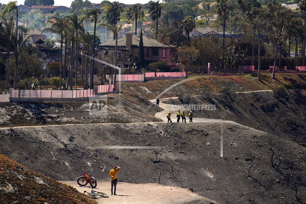 Marcio Jose Sanchez Firefighters and residents stand on a fire road where the Coastal Fire jumped and burned several homes Thursday, May 12, 2022, in Laguna Niguel, Calif. (AP Photo/Marcio Jose Sanchez)