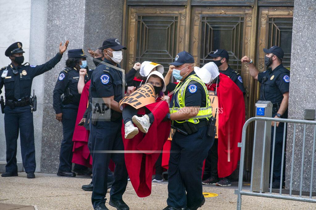 Jose Luis Magana Demonstrators opposed to the confirmation of President Donald Trump's Supreme Court nominee, Judge Amy Coney Barrett, dressed as characters from "The Handmaid's Tale," are arrested after blocking an entrance of the Dirksen Senate office building, Thursday, Oct. 22, 2020, on Capitol Hill in Washington.(AP Photo/Jose Luis Magana)
