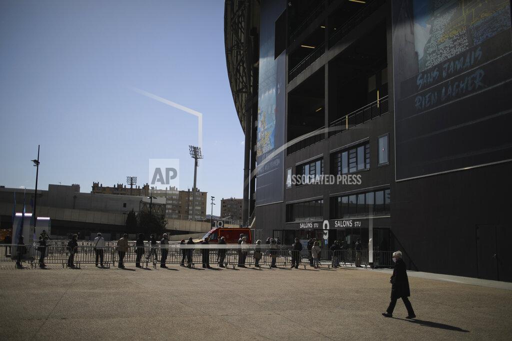Daniel Cole Residents line up to wait at a vaccination site set up in the Marseille soccer Velodrome stadium, during a presentation to the media, in Marseille, Monday, March 15, 2021. The government plans to inoculate 10 million citizens by mid-April, 20 million by mid-May and a total of 30 million, or two-thirds of the adults by summer. (AP Photo/Daniel Cole)