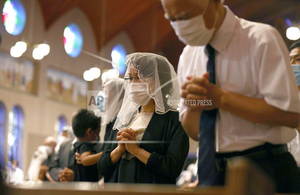 Uncredited Christians, wearing face masks, pray for the victims of U.S. atomic bombing during a mass at Urakami Cathedral in Nagasaki, southern Japan, Sunday, Aug. 9, 2020. Nagasaki marked the 75th anniversary of the atomic bombing on Sunday. (Kyodo News via AP)
