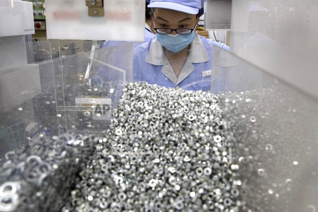 Ng Han Guan In this Wednesday, May 13, 2020 photo, a worker at SMC China, a Japanese joint venture pneumatic engineering company, assembles products at a factory in Beijing. The United States, Japan and France are prodding their companies to rely less on China to make the world’s smartphones, drugs and other products. But even after the coronavirus derailed global trade, few are willing to give up access to its skilled workers, vast market and efficient suppliers by moving factories closer to home.(AP Photo/Ng Han Guan)