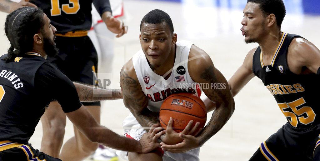 Arizona guard James Akinjo (13) gets manhandled splitting the lane between Washington guard Marcus Tsohonis (0), left, and guard Quade Green (55) in the second half of an NCAA college basketball game Saturday, Feb. 27, 2021, in Tucson, Ariz. (Kelly Presnell/Arizona Daily Star via AP)