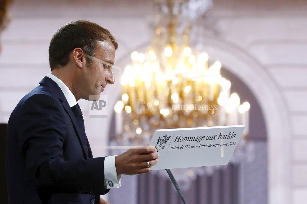 Gonzalo Fuentes French President Emmanuel Macron holds a sign as he delivers a speech during a meeting in memory of the Algerians who fought alongside French colonial forces in Algeria's war, known as Harkis, at the Elysee Palace in Paris, Monday, Sept. 20, 2021. Macron's speech is the latest step in his efforts to reconcile France with its dark colonial past, especially in Algeria. (Gonzalo Fuentes/Pool Photo via AP)
