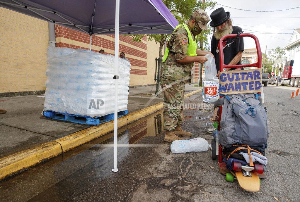 Photo By David Grunfeld A National Guard soldier from Kansas helps Magazine Gene load up on ice at the Dryades YMCA, Drive-Thru and walk-up supply Distribution site in New Orleans, La. Tuesday, Sept. 7, 2021. Hundreds of thousands of homes and businesses still didn’t have power Tuesday and more than half of the gas stations in two major cities were still without fuel more than a week after Hurricane Ida slammed into Louisiana, splintering homes and toppling electric lines across the state. (David Grunfeld, NOLA.com/The Times-Picayune/The New Orleans Advocate via AP)