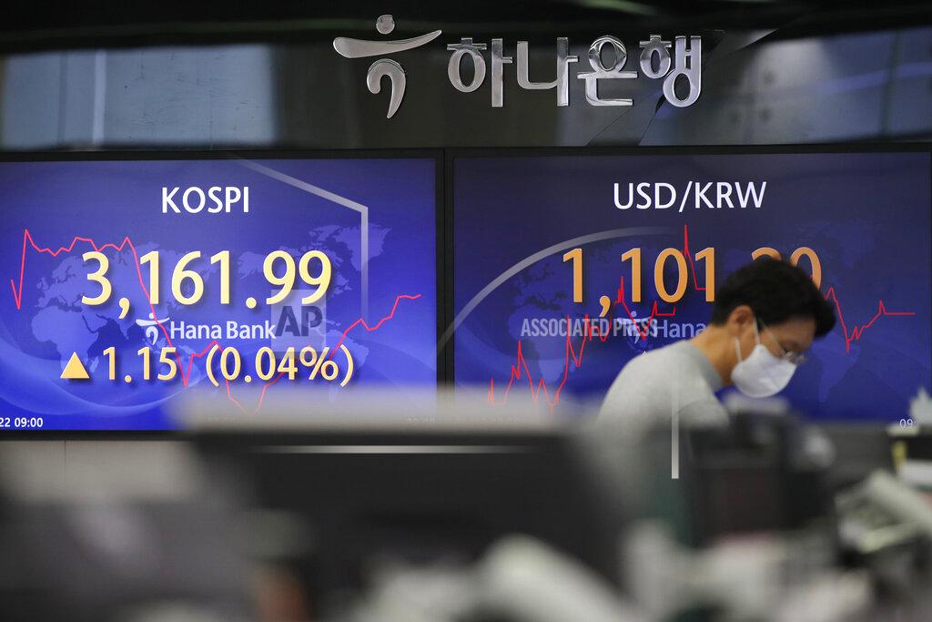 Lee Jin-Man A currency trader walks by the screens showing the Korea Composite Stock Price Index (KOSPI), left, and the foreign exchange rate between U.S. dollar and South Korean won at the foreign exchange dealing room in Seoul, South Korea, Friday, Jan. 22, 2021. Asian stock markets retreated Friday after a resurgence of coronavirus infections in China and a rise in cases in Southeast Asia. (AP Photo/Lee Jin-man)