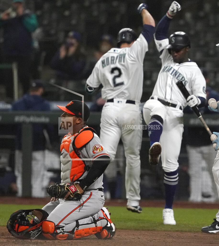 Ted S. Warren Baltimore Orioles catcher Pedro Severino kneels by the plate as Seattle Mariners' Tom Murphy (2) is greeted by Taylor Trammell, right, after Murphy hit a solo home run in the fifth inning of a baseball game, Monday, May 3, 2021, in Seattle. (AP Photo/Ted S. Warren)