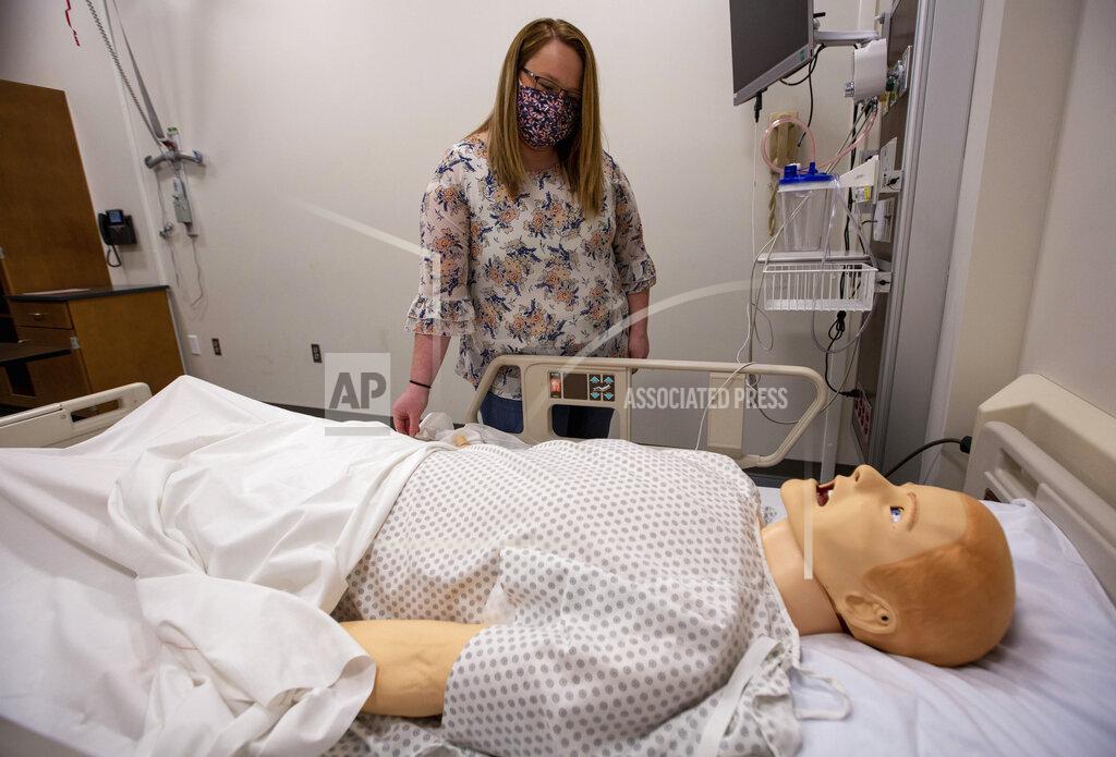 Daniel Lin In this May 11, 2021 photo, Heather Fitzgerald, a recent Blue Ridge Community College nursing graduate, attaches a pulse oximeter to a mannequin in a nursing lab in Weyers Cave, Va. (Daniel Lin/Daily News-Record via AP)