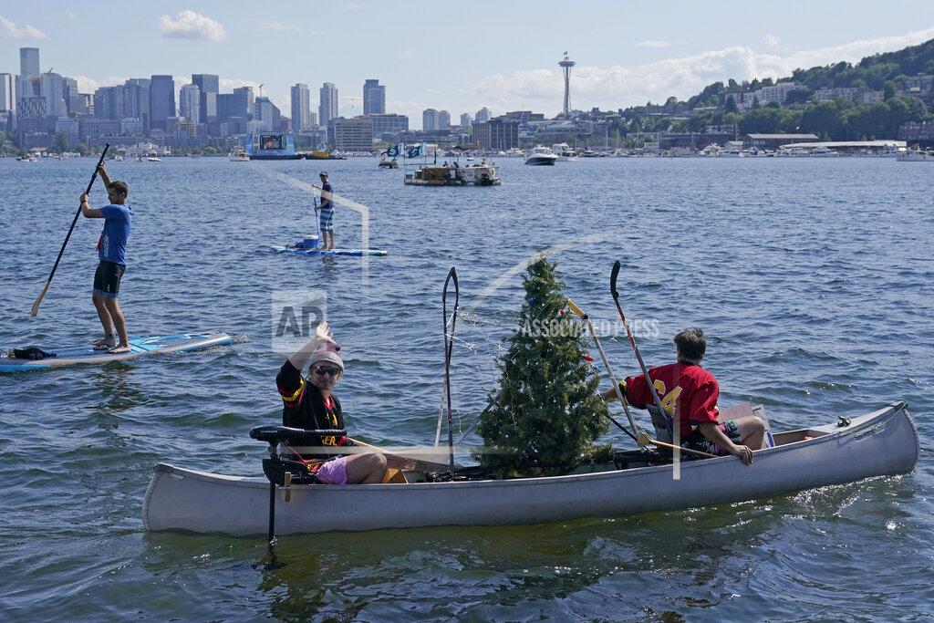 Ted S. Warren People paddle a canoe with a Christmas tree held up by hockey sticks as they float on Lake Union with the Space Needle in the background, Wednesday, July 21, 2021, in Seattle near the park where the Seattle Kraken NHL hockey expansion draft event was taking place. (AP Photo/Ted S. Warren)