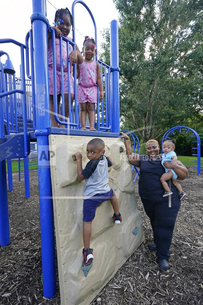 Rogelio V. Solis Brianne Epps of Jackson, Miss., 28, is a single mother with son Nolan Epps, 11 months in her arms, son Micah Epps, 4, left, and daughters Laila Barnes, 6, top right and Kaylee Barnes, 8, top left, at a playground at their apartment complex in Jackson, Miss., Wednesday, July 21, 2021. Epps earns $9 an hour working with infants and toddlers in a childcare center, but she has a bigger dream of operating a soul food catering business. (AP Photo/Rogelio V. Solis)