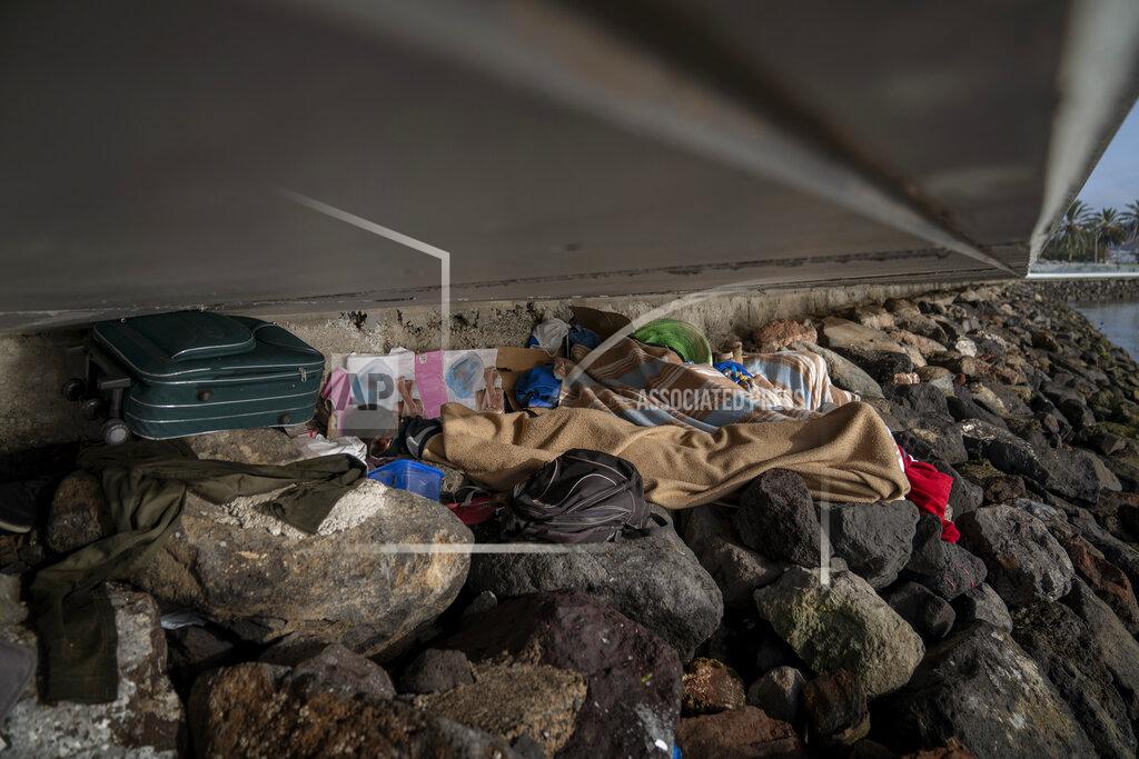 Emilio Morenatti Khalid, a migrant from Gambia, sleeps on a breakwater under a bridge in Gran Canaria island, Spain, on Saturday, Aug. 22, 2020. The striking shift in migration back to the Canary Islands has raised alarms at the highest levels of the Spanish government. (AP Photo/Emilio Morenatti)